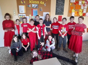 Grupa uczniów ubrana na czerwono pozuje do zdjęcia w szkolenj sali